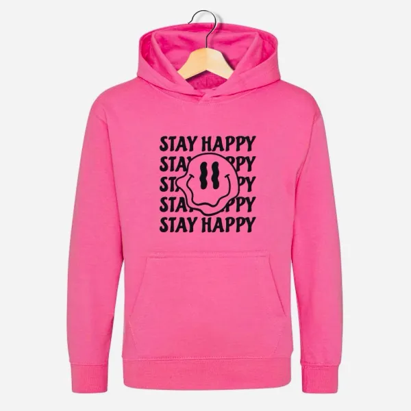 Adult hoodie in pink which says Stay Happy as a background to a wobbly smiley face